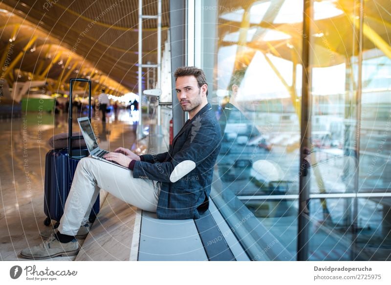 man sitting at the airport using laptop and mobile phone next to the window Airport Youth (Young adults) Smiling Wait Story Window Sun Sunrise Cellphone