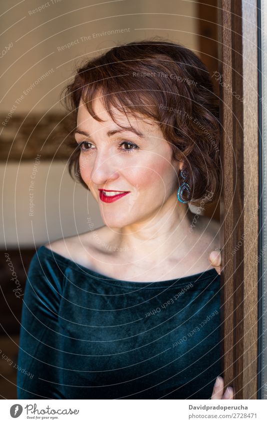 Portrait of a mature woman posing thoughtful throughout the window Portrait photograph Woman Red-haired Mature Old Human being Window Considerate Stand