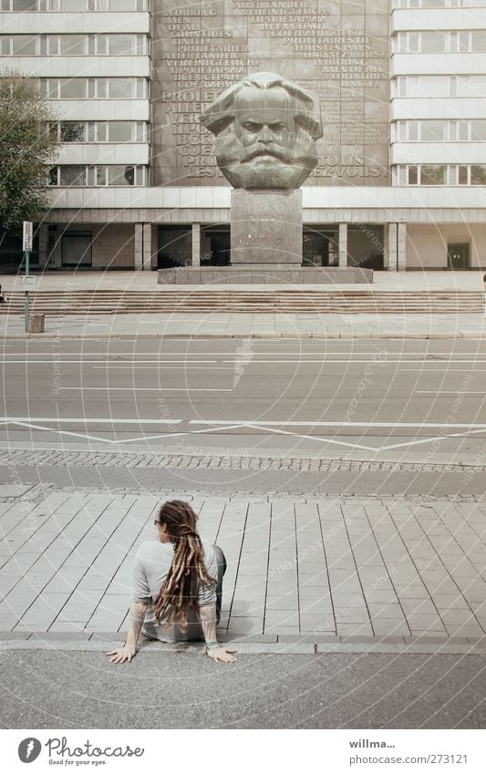 Youth with rastas squats casually all alone on roadside in front of monument to Karl Marx Youth (Young adults) Street Marx Monument ponder chill urban youthful