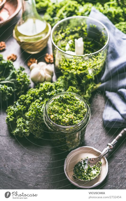 Green kale pesto in glass on dark rustic kitchen table background with ingredients, top view. Kale preparation. Healthy detox vegetables . Clean eating and dieting concept.