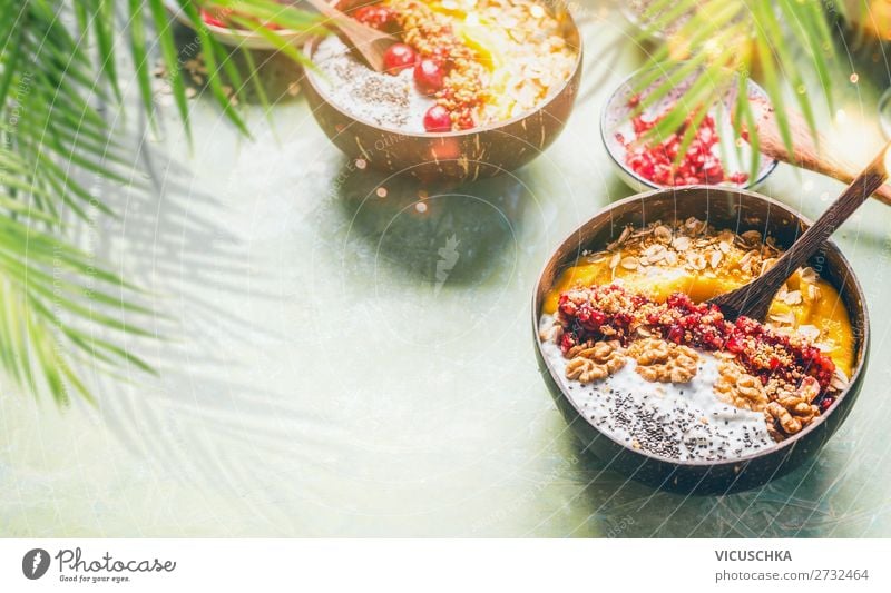 Smoothie mango bowl with chia seeds yogurt pudding and cranberries, nuts, oatmeal topping in coconut shells with spoon. Healthy clean breakfast food. Copy space for your text or design