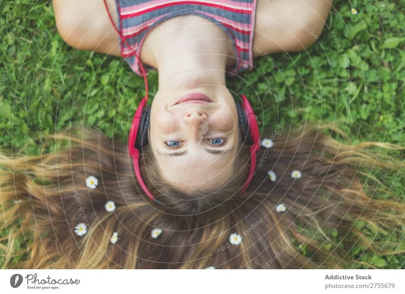 Excited girl in headphones on grass Woman Expressive Headphones Posture Grass Lie (Untruth) Park facial Flower Excitement Model Expression Style