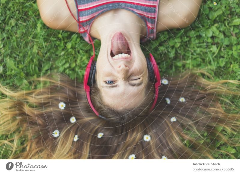 Excited girl in headphones on grass Woman Expressive Headphones Posture Grass Lie (Untruth) Park facial Flower Excitement Model Expression Style