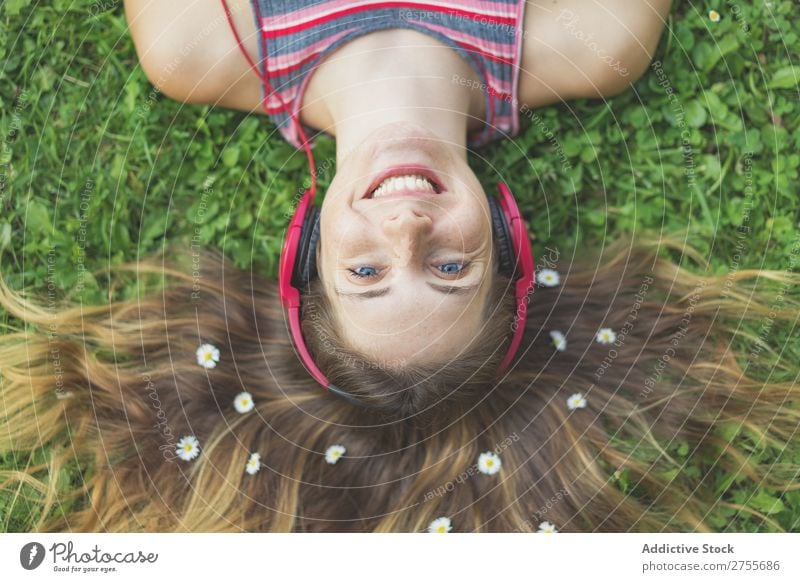 Excited girl in headphones on grass Woman Expressive Headphones Posture Grass Lie (Untruth) Park facial Flower Excitement Model Expression Style