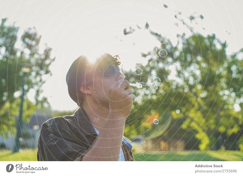 Man blowing soap bubbles in park Hipster Park Soap bubble romantic handsome Youth (Young adults) Playful Easygoing Modern Blow Posture Summer Playing Happiness