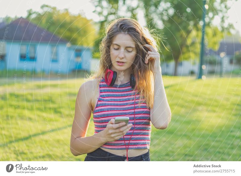 Stylish girl posing with gadgets Woman PDA Posture Relaxation Summer Nature Headphones Feminine Music Contentment Dream Meadow Hold device Charming