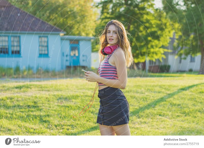 Stylish girl posing with gadgets Woman PDA Posture Relaxation Summer Nature Headphones Feminine Music Contentment Dream Meadow Hold device Charming