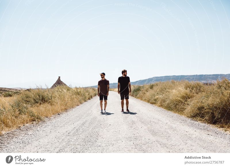 Two men walking along road Man prairie Street Vacation & Travel Lifestyle Human being Adults Nature Adventure Trip Tourist Landscape Grass Vantage point Sky