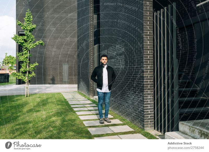 Trendy young man walking in the street looking away thoughtful pensive stylish brick wall standing confident cool person portrait modern model fashionable male