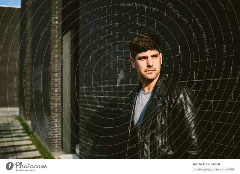 Young handsome man over a dark brick wall serious sunglasses confident young cool person portrait modern model fashionable male casual guy adult caucasian