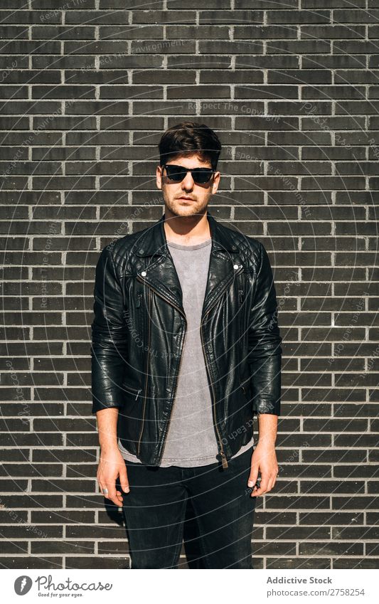 Young man over a brick wall stylish pensive thoughtful looking at camera sitting stairs confident young cool person portrait modern model fashionable male