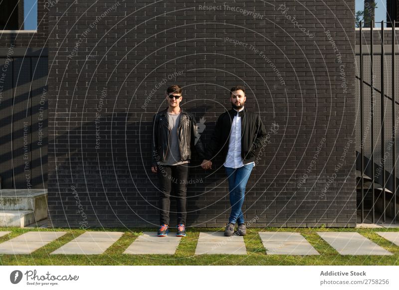 Alternative couple at brick wall Couple Stand Wall (building) Brick holding hands Looking into the camera Posture Homosexual In pairs Man Love 2 Together