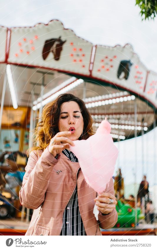 Woman with cotton candy in the park woman merry-go-round person pink female pretty sweet food eat sugar fun lifestyle portrait young smile holding snack outside