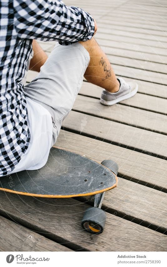 Tattooed man sitting on skateboard Man skateboarder Sit Skateboard Ice-skates Town Sports Skateboarding Youth (Young adults) Board Ice-skating Human being