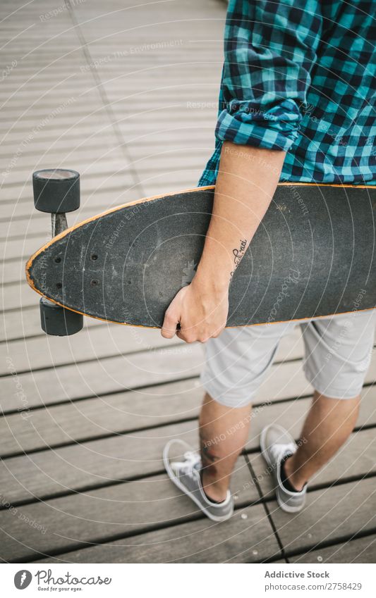 Man with tattoos holding skateboard at shore. Back view. Skateboard Coast Beach Leisure and hobbies Summer Multicoloured youngster Action Youth (Young adults)