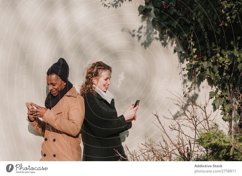 Couple in warm clothes with smartphones multiethnic Style Street PDA using Stand Easygoing Beautiful Mixed race ethnicity Black Youth (Young adults) Together