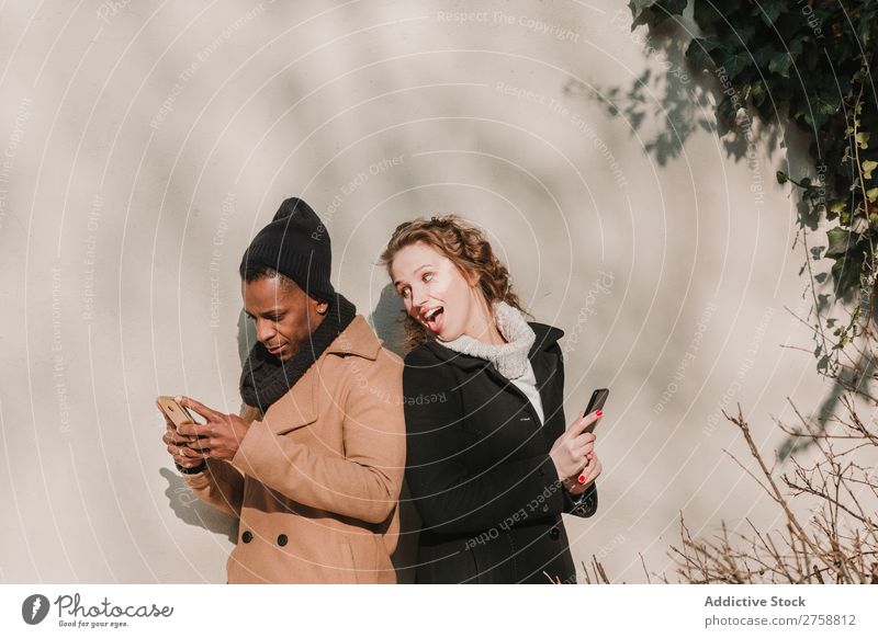 Couple in warm clothes with smartphones multiethnic Style Street PDA using Stand Easygoing Beautiful Mixed race ethnicity Black Youth (Young adults) Together