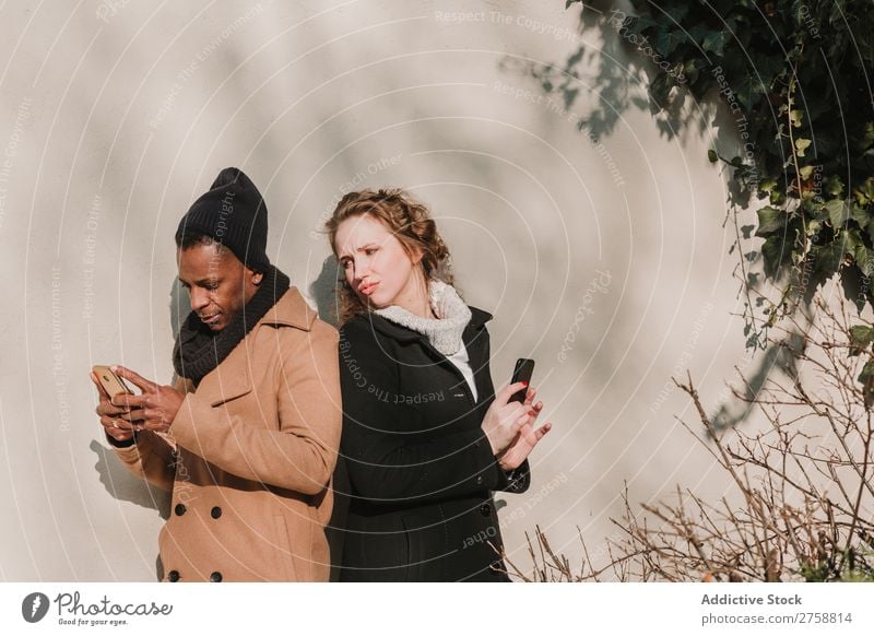 Couple in warm clothes with smartphones multiethnic Style Street PDA using Stand Easygoing Beautiful Mixed race ethnicity Black Youth (Young adults) Together