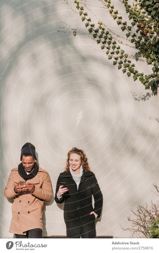 Couple in warm clothes with smartphones multiethnic Style Street PDA using Stand Easygoing Beautiful Mixed race ethnicity Black Youth (Young adults) Together