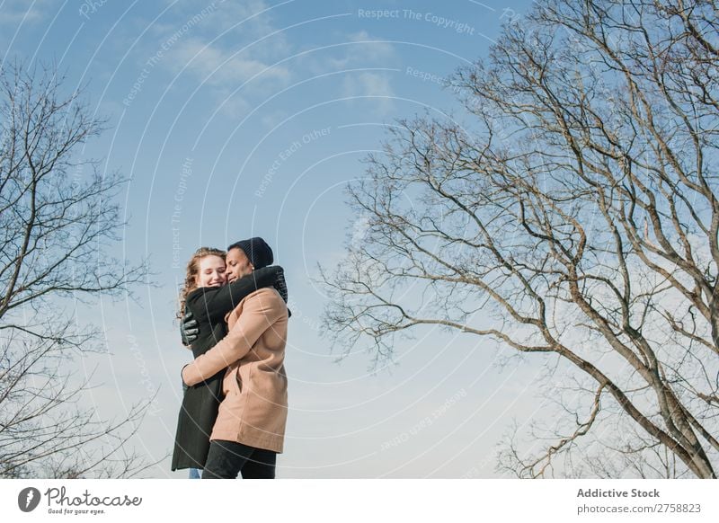 Couple embracing at naked trees multiethnic Style Street warm clothes Tree Leafless Naked Easygoing Beautiful Mixed race ethnicity Black Youth (Young adults)