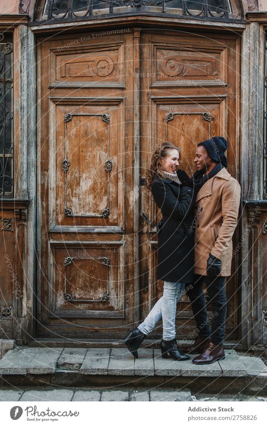 Couple embraced at vintage door multiethnic Style Street warm clothes Wood Door grungy Old Easygoing Beautiful Mixed race ethnicity Black Youth (Young adults)