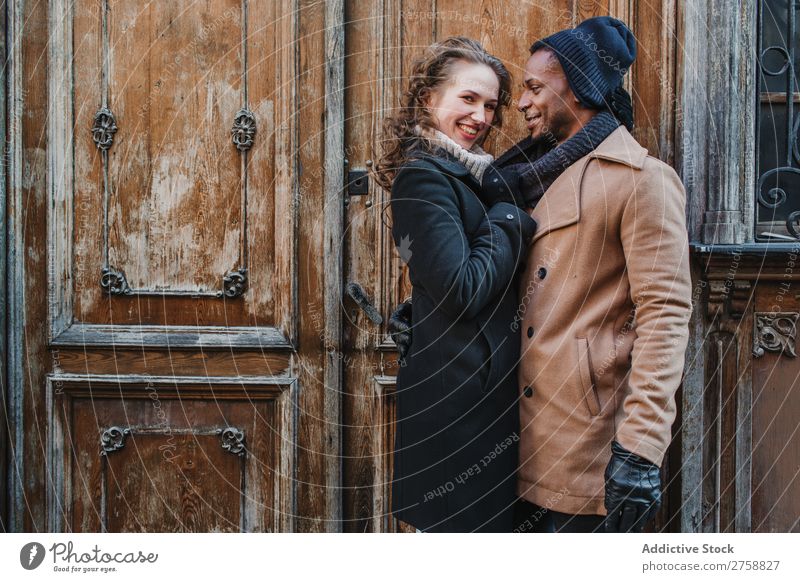 Couple embraced at vintage door multiethnic Style Street warm clothes Wood Door grungy Old Easygoing Beautiful Mixed race ethnicity Black Youth (Young adults)