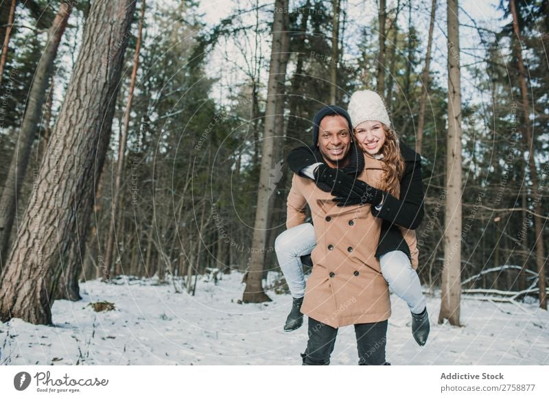 Couple having fun in winter forest multiethnic Style warm clothes Easygoing Nature Forest Winter Snow piggyback Beautiful Mixed race ethnicity Black