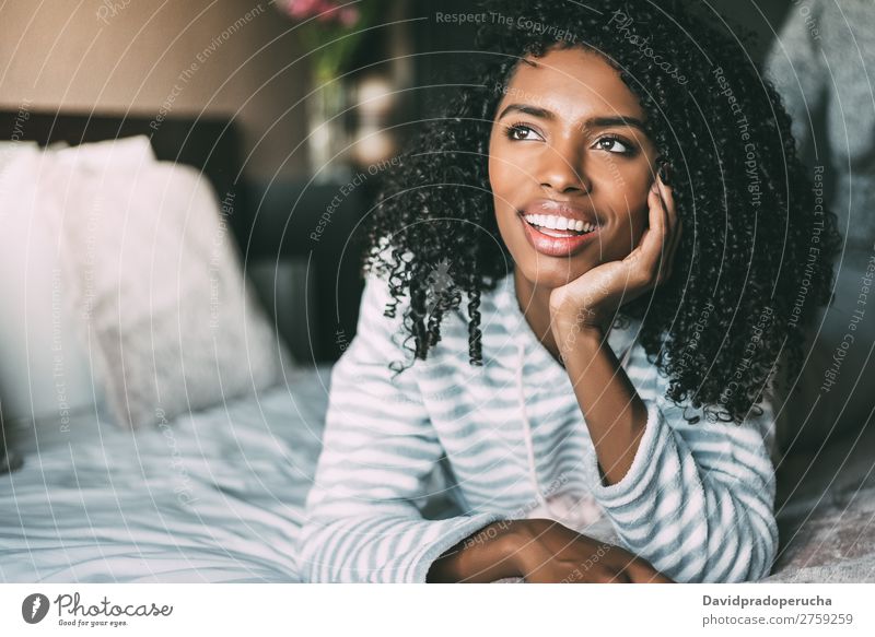 close up of a pretty black woman with curly hair smiling and lying on bed looking away Woman Bed Portrait photograph Close-up Lie (Untruth) Black Smiling