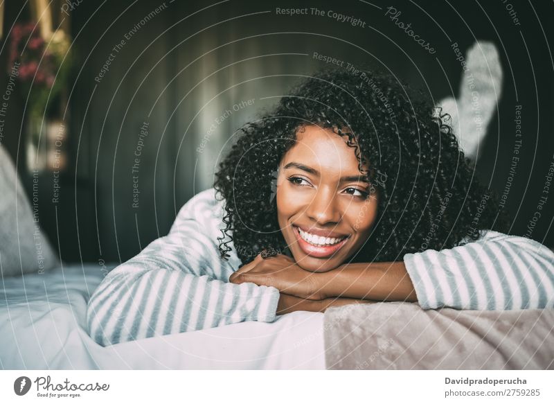 close up of a pretty black woman with curly hair smiling and lying on bed looking away Woman Bed Portrait photograph Close-up Lie (Untruth) Black Smiling