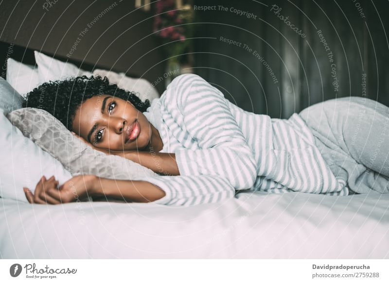 close up of a pretty black woman with curly hair smiling and lying on bed looking away Woman Bed Portrait photograph Close-up Lie (Untruth) Black Smiling