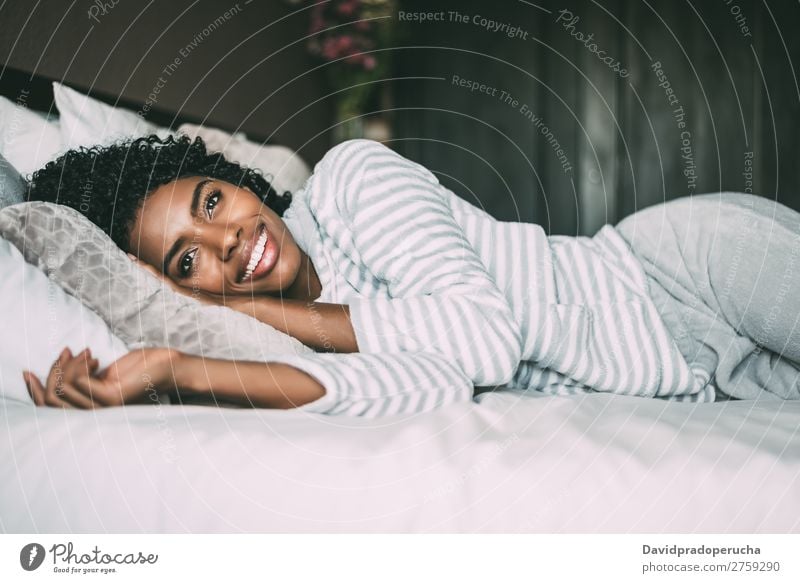 close up of a pretty black woman with curly hair smiling and lying on bed looking away Woman Bed Portrait photograph Close-up Lie (Untruth) Black Smiling