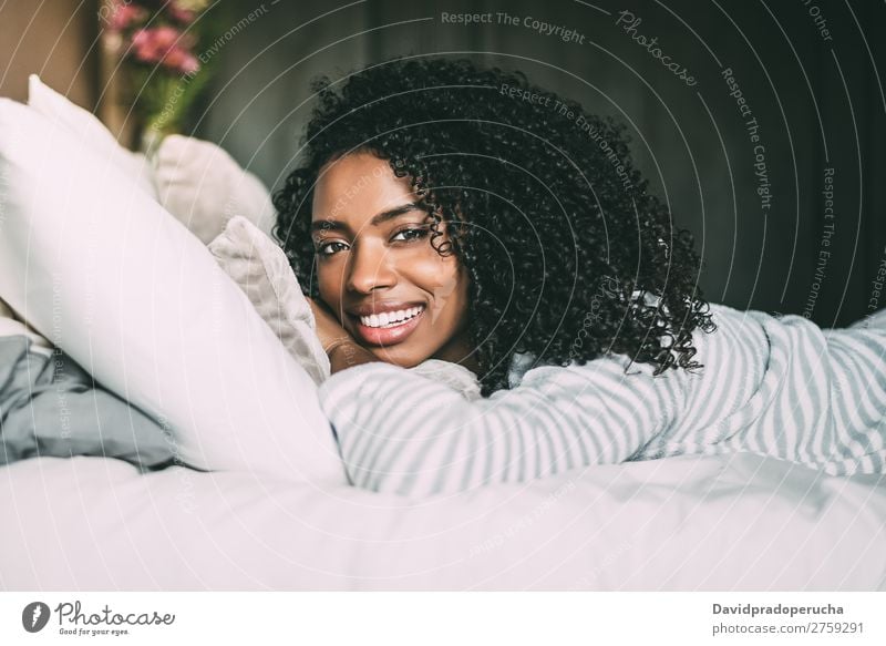 close up of a pretty black woman with curly hair smiling and lying on bed looking at the camera Woman Bed Portrait photograph Close-up Lie (Untruth) Black