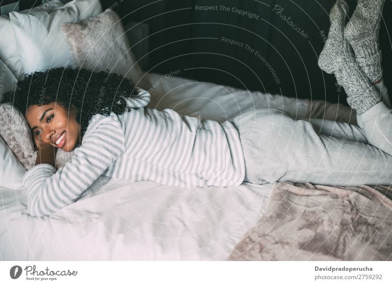 close up of a pretty black woman with curly hair smiling and lying on bed looking away Woman Bed Portrait photograph Close-up Lie (Untruth) Black Smiling