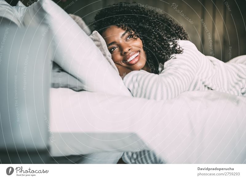 close up of a pretty black woman with curly hair smiling and lying on bed looking away Woman Bed Portrait photograph Close-up Lie (Untruth) Black Smiling