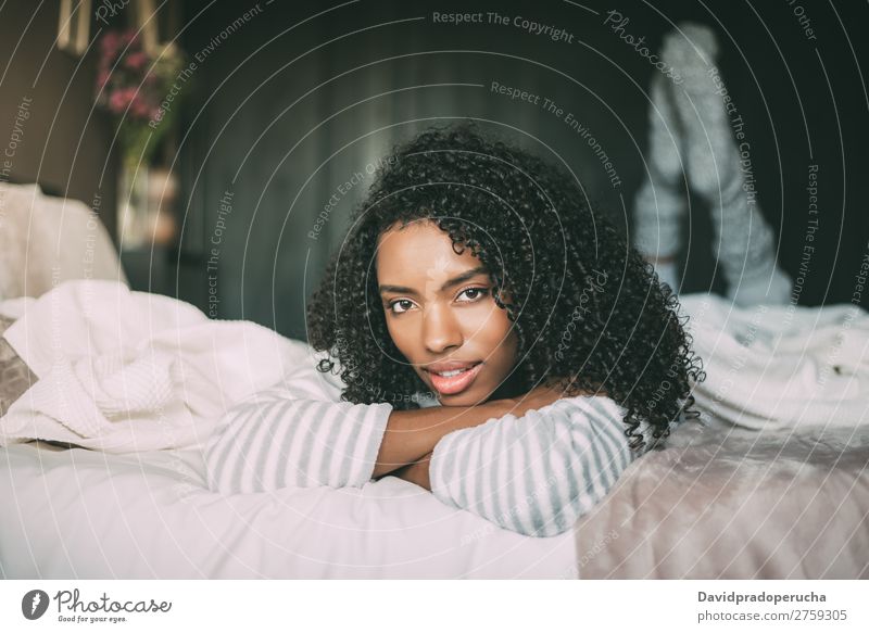 close up of a pretty black woman with curly hair smiling and lying on bed looking at the camera Woman Bed Portrait photograph Close-up Lie (Untruth) Black