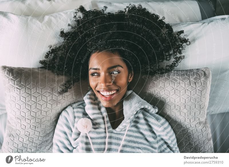 Beautiful black woman lying on bed looking at the camera smiling Woman Bed Black Considerate Smiling African pretty Bird's-eye view Close-up Curly hair