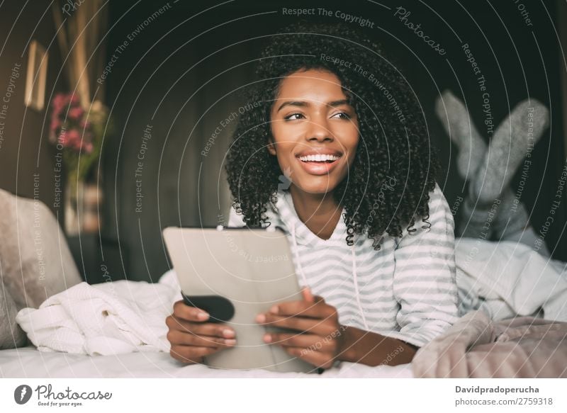 close up of a pretty black woman with curly hair smiling and using phone on bed looking away Woman Bed Portrait photograph Close-up PDA Telephone Mobile