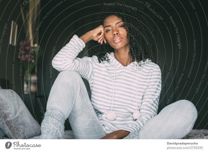 Beautiful thoughtful black woman sit on bed looking at the camera Woman Bed Black Considerate African Crops pretty Sit Close-up Curly hair Interior shot Resting