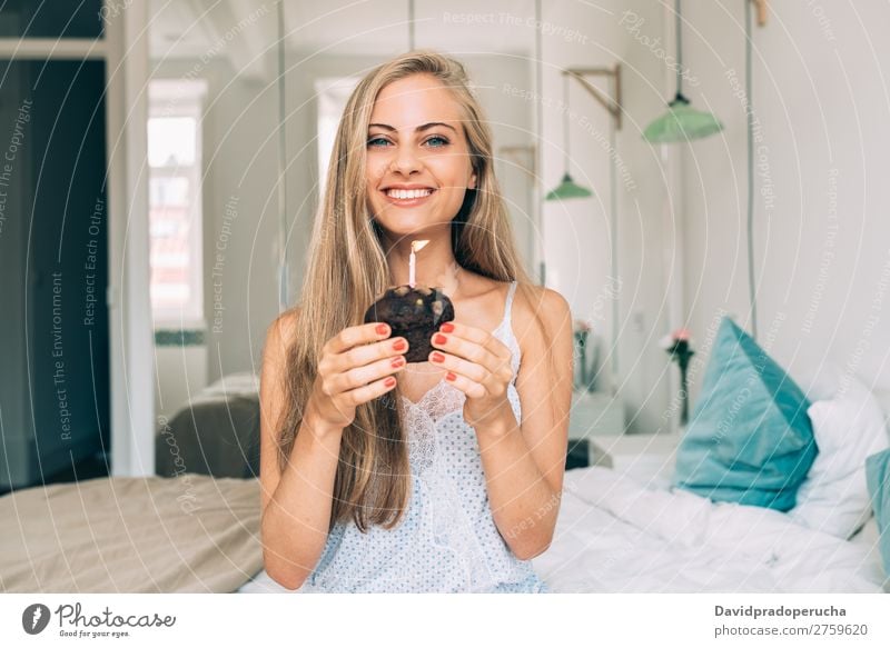 Young beautiful blonde woman in the bed blowing a candle in a chocolate muffin Woman Bed Bedroom Blonde Portrait photograph Muffin Cake Blow Candle Birthday