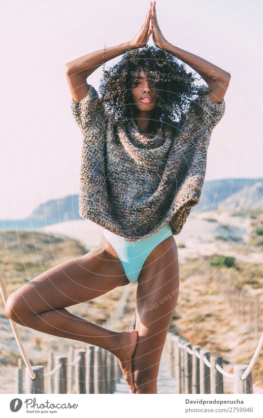 Young black woman doing yoga in a wooden foot bridge by the beach Background picture Yoga Beach Bikini Black Practice Bridge Coast Curly hair Destination Feet