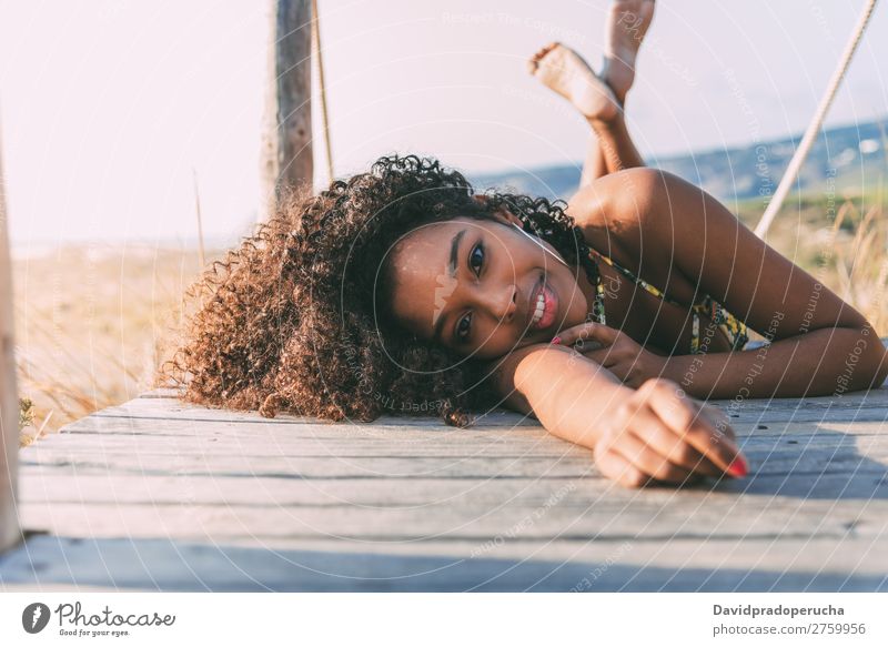 Beautiful young black woman lying down in a  wooden foot bridge at the beach Background picture Beach Bikini Black Bridge Coast Curly hair Destination Girl Cute