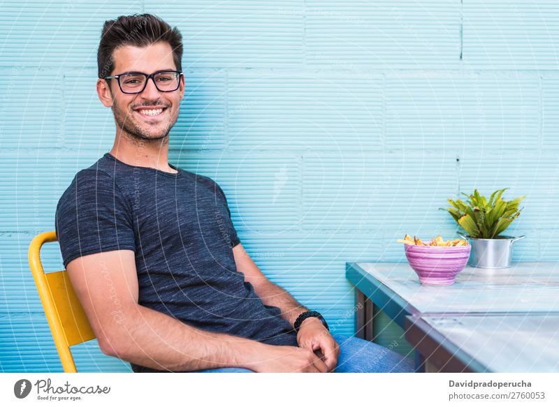 Happy young man seating in a restaurant Adults Loneliness Attractive Beautiful Blue Bright Caucasian Coffee Café Multicoloured enjoying Food Fries Guy handsome