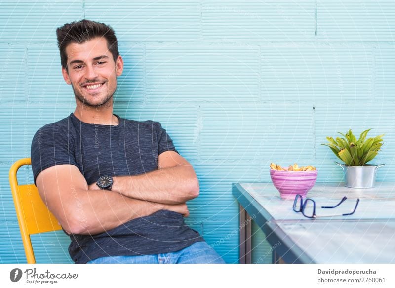 Happy young man seating in a restaurant Adults Loneliness Attractive Beautiful Blue Bright Caucasian Coffee Café Multicoloured enjoying Food Fries Guy handsome