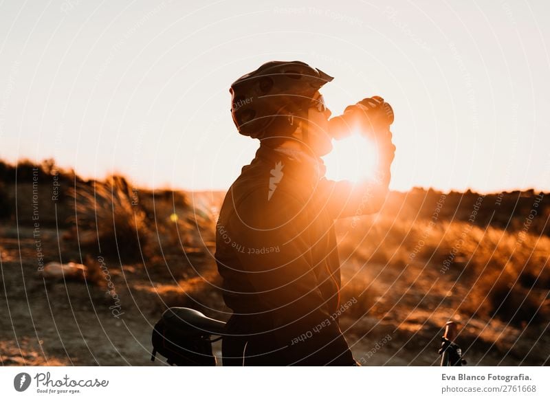 Cyclist drinking water on the bike at sunset. Sports Beverage Drinking Drinking water Lifestyle Leisure and hobbies Adventure Summer Sun Mountain Cycling