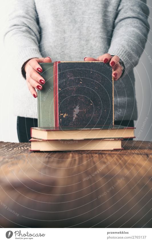 Young woman holding old books on table in antique bookstore Lifestyle Shopping Relaxation Leisure and hobbies Reading School Study Human being Woman Adults