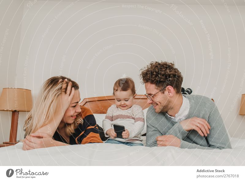 Cheerful couple with child on bed Family & Relations Mother Father Child PDA Playing Human being Hotel Room Bedroom Home Interior design Furniture