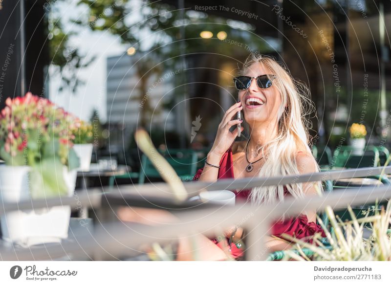 Happy blonde beautiful woman using a mobile phone drinking a cup of coffee in a terrace Woman Smiling Coffee Cup Cellphone PDA Sunglasses Terrace Restaurant