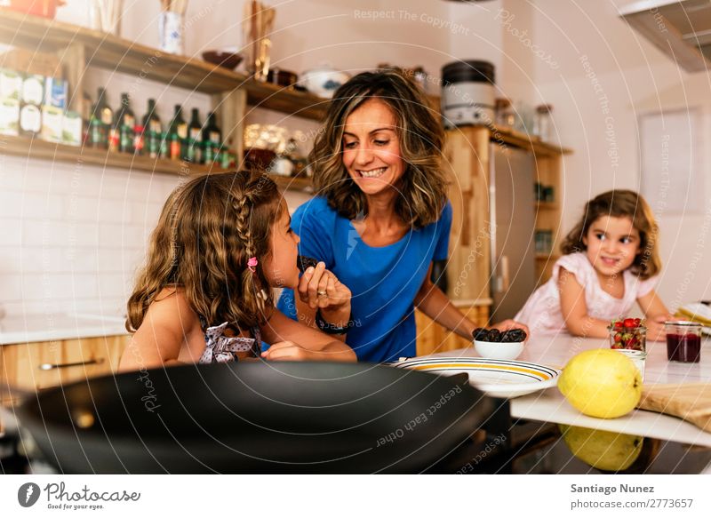 Little sisters cooking with her mother in the kitchen. Mother Child Girl Cooking tasting Kitchen Chocolate Ice cream Daughter Day Happy Joy Family & Relations