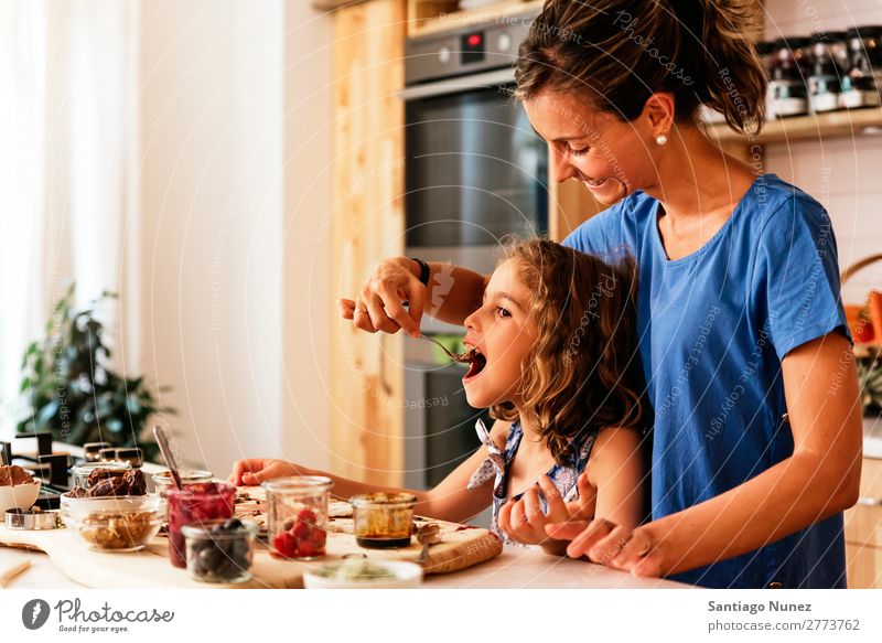 Little girl cooking with her mother in the kitchen. Mother Girl Cooking Kitchen Chocolate tasting savoring Daughter Day Happy Joy Family & Relations Love Baking