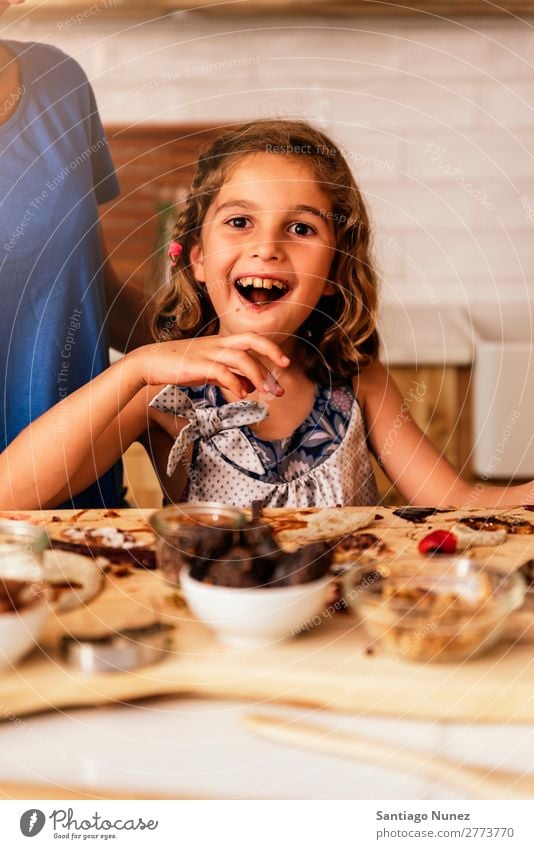 Little girl cooking with her mother in the kitchen. Girl Child Nutrition To feed savoring Eating tasting enjoying Portrait photograph Appetite Smiling Laughter